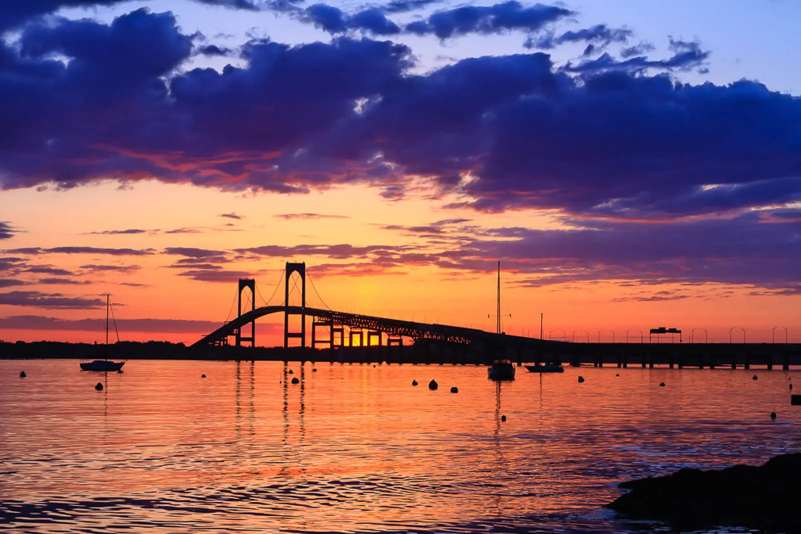 The Newport Bridge under dramatic, colorful skies at sunset, inspiring awe, reflection, and calm.