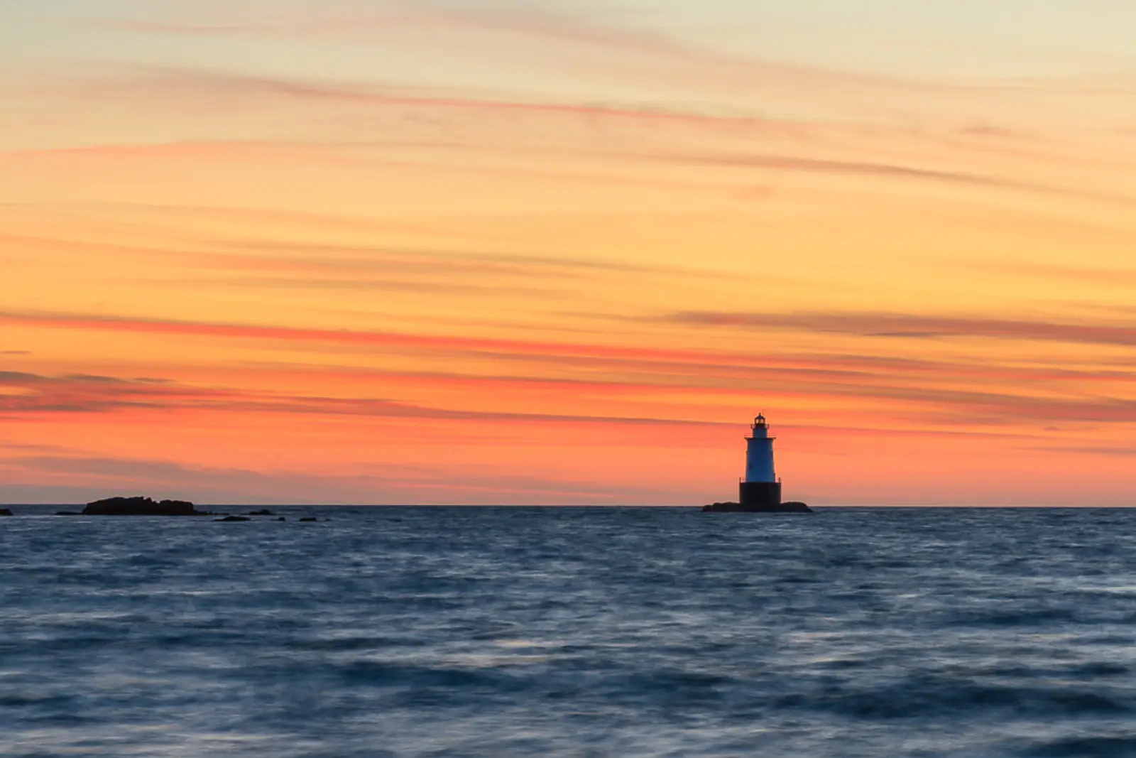 A historic lighthouse at Sakonnet Point standing tall against a colorful sky, symbolizing guidance, hope, and calm.